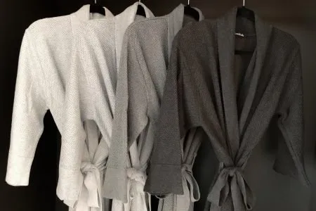 Three bemboka bathrobes in soft, neutral colours hanging in a row