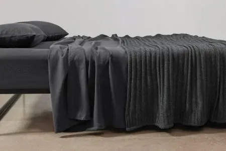 Angora and merino wool throw layered over Belgian linen sheeting, showcasing luxurious texture and natural fibres.