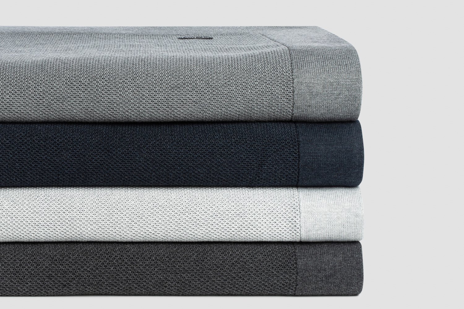 Stack of folded bamboo blankets in soft grey and charcoal tones.