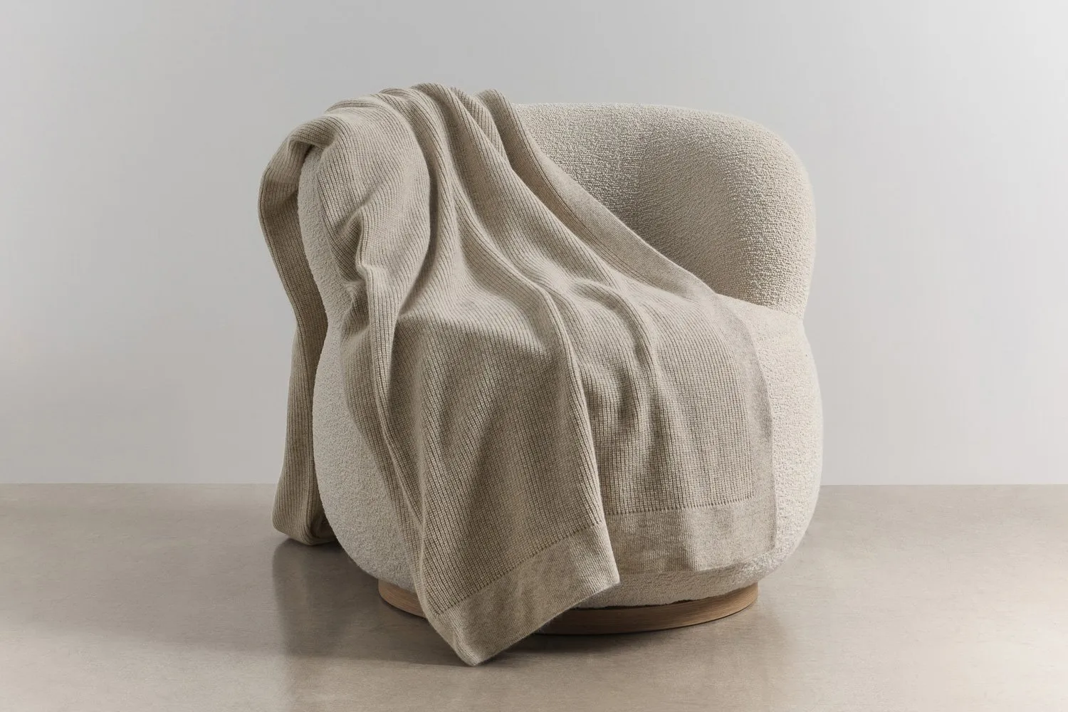 Chain rib angora and merino wool throw draped over a textured armchair, showcasing soft knit texture, warmth and insulation in a calm interior setting.