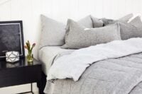Layered winter bedding with quilted blanket, crisp white sheets and soft grey pillows styled for breathable warmth and everyday comfort.