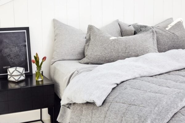 Layered winter bedding with quilted blanket, crisp white sheets and soft grey pillows styled for breathable warmth and everyday comfort.