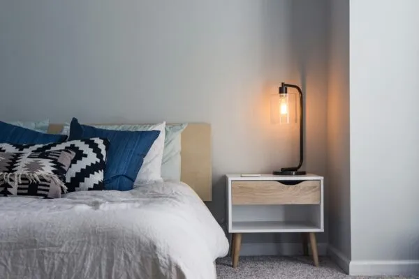 arm bedside lighting and layered natural bedding create a calm bedroom designed for comfort during the cooler months.